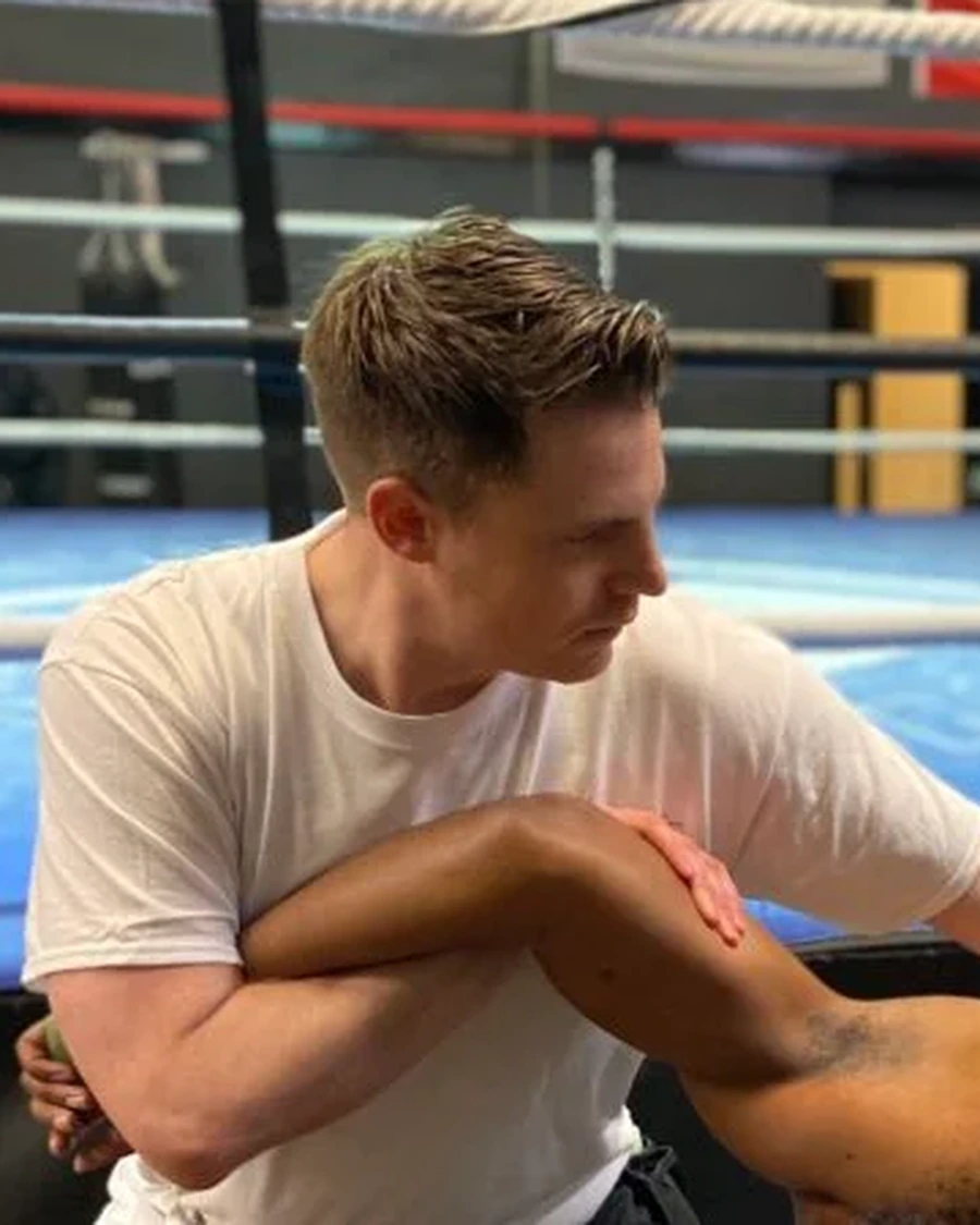 Eden Simpson working on a client's shoulder and arm at a boxing gym