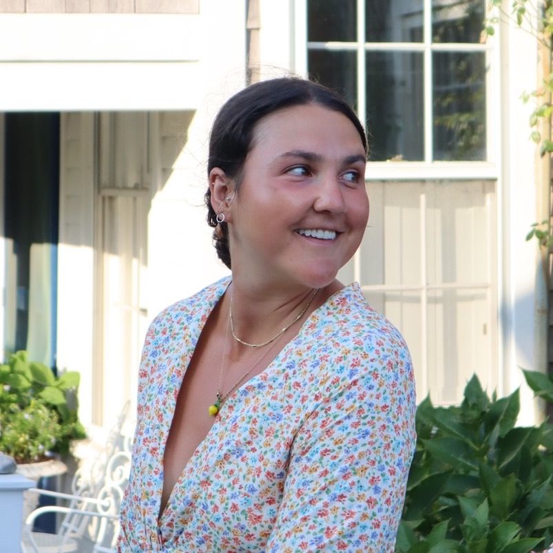 Hannah Moore smiling outdoors in a floral wrap dress